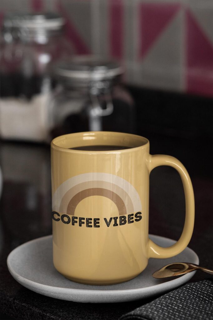 A coffee cup show a rainbow in coffee colors and the words coffee vibes underneath the rainbow.