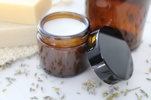 Cream lotion in a small amber glass jar with the lid leaning against it.