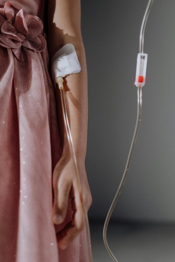girl with pink dress, has a iv in her arm